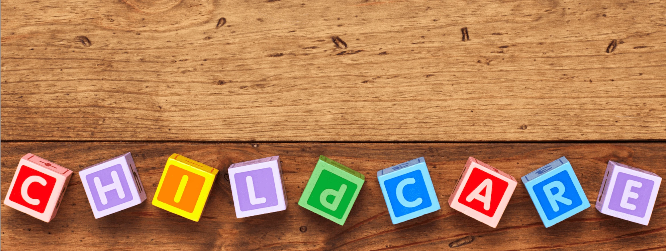 Colorful wooden blocks spelling CHILDCARE on wooden floor