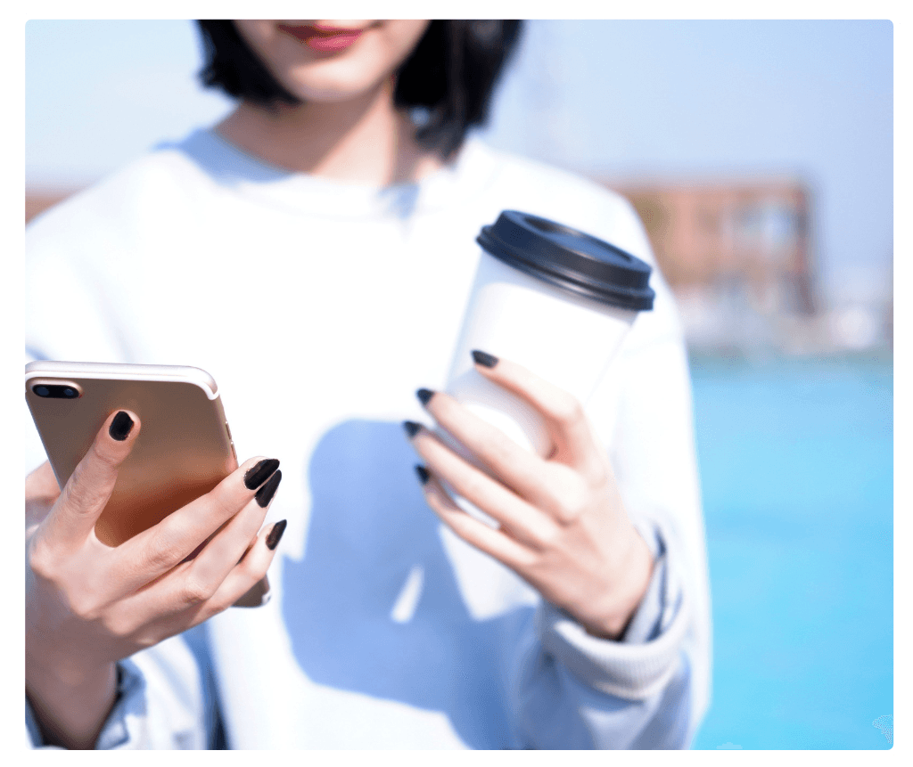 Employee checking phone to request leave while holding coffee