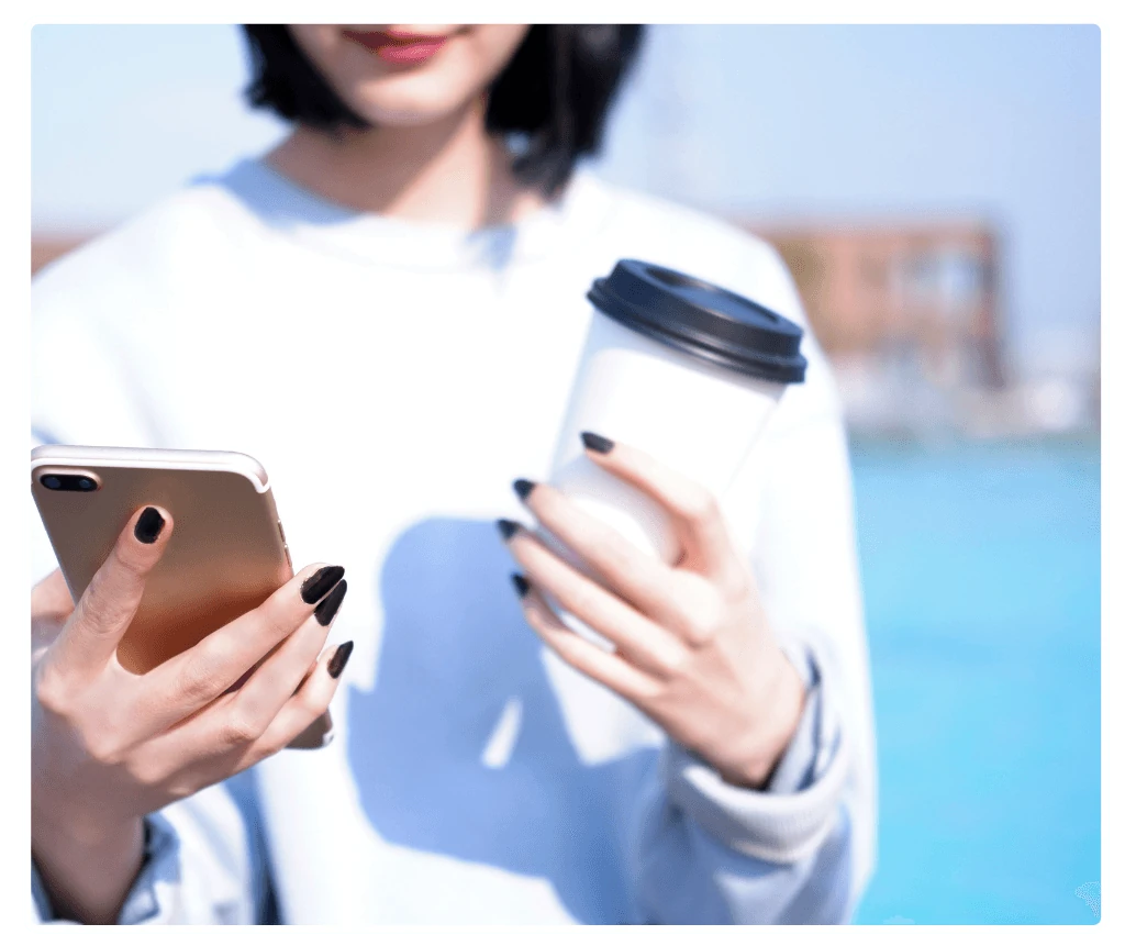 Employee checking phone to request leave while holding coffee