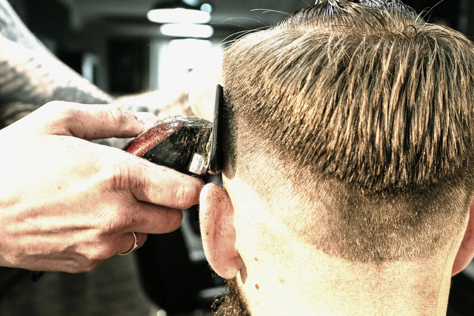 A barber clipping a client's hair in a barbershop