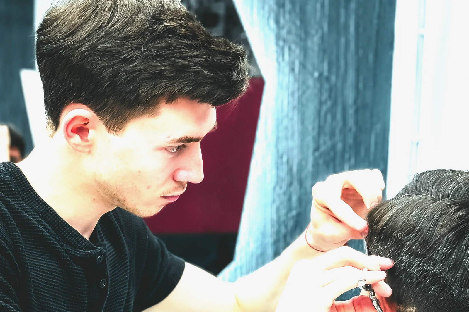 A barber finishing a client's cut with scissors