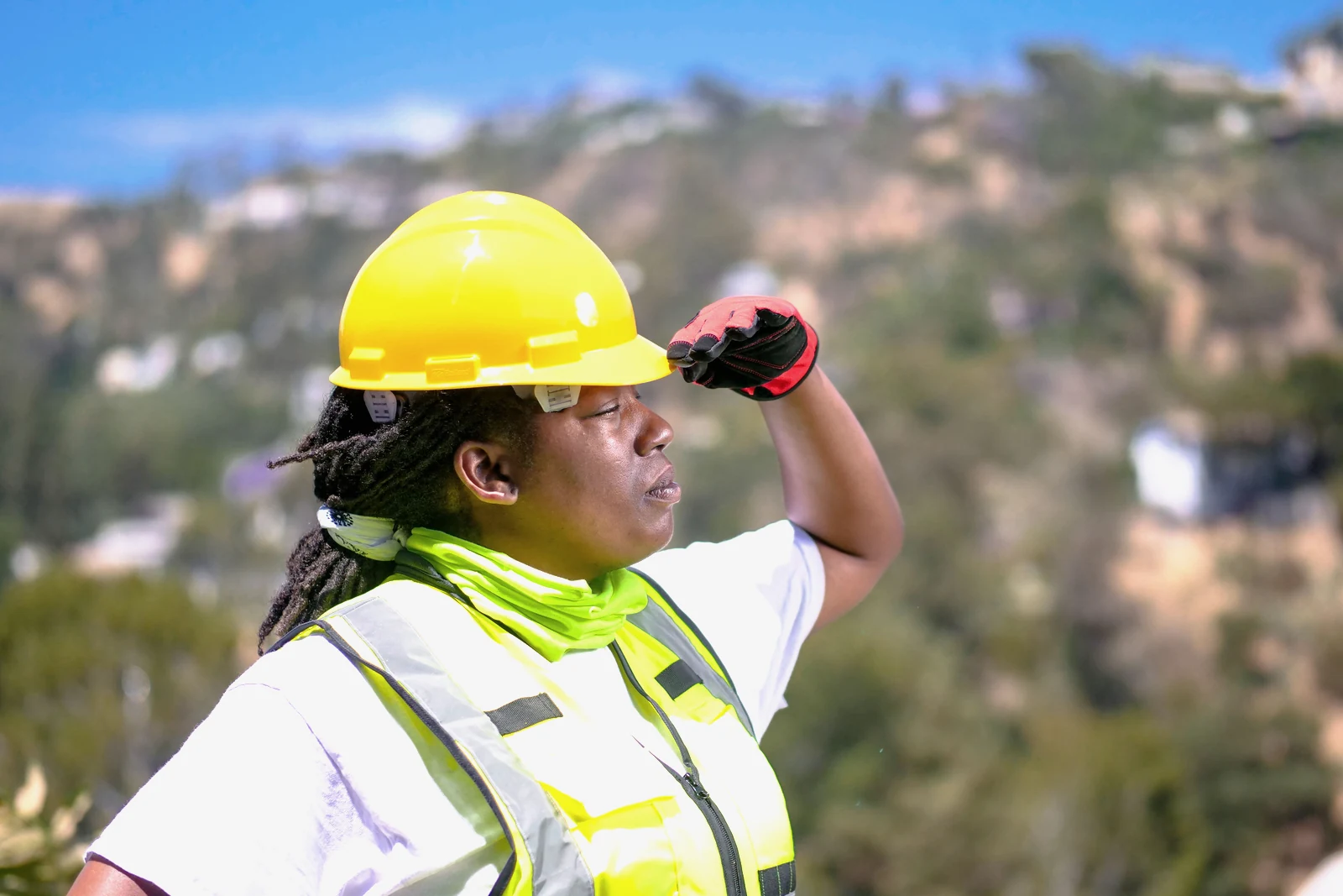 A site worker in a hard hat and hi-vis surveying an open mine site