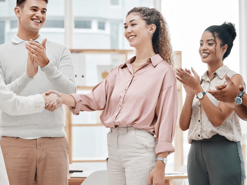 Team applauding and shaking hands with a departing colleague on a positive exit