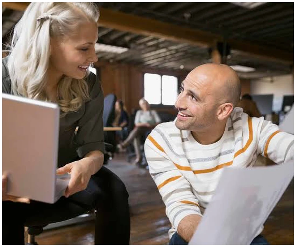 Two colleagues reviewing goals and progress on a laptop