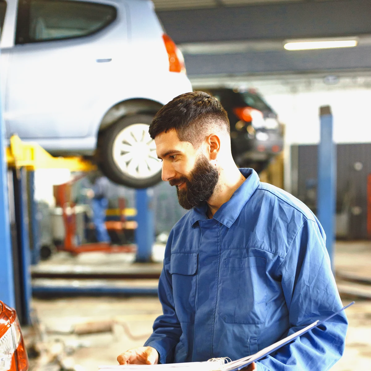 A workshop owner in overalls checking figures on a clipboard