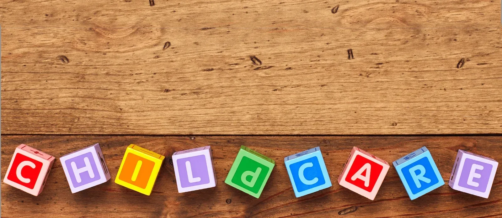 Children's wooden alphabet blocks spelling CHILDCARE along a timber floor